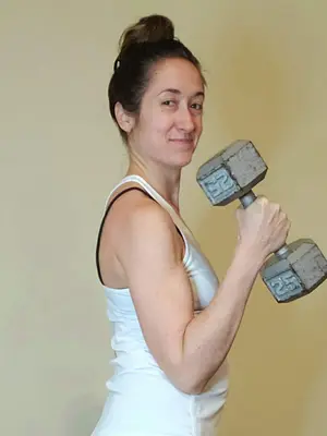 bethany holding a large dummbell while doing a curl to show p90x generation next results are being able to lift heavier as one