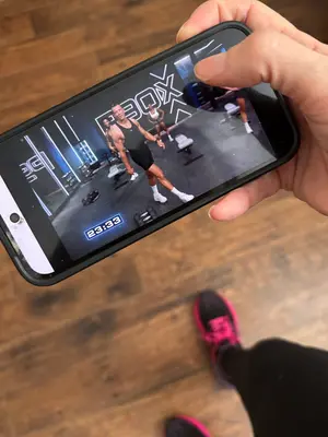 p90x generation next workout being displayed on cell phone app with bethany holding in hand with workout sneakers on