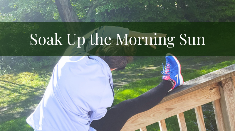 bethany outside with morning sunshine through trees doing a hamstring stretch