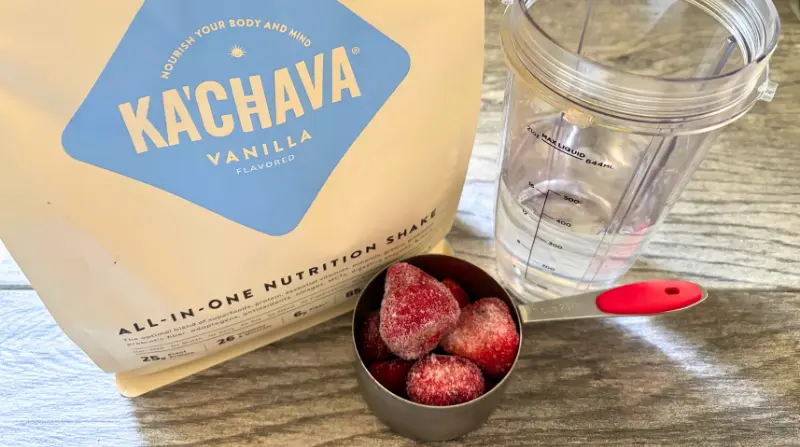 kachava bag with strawberries in measuring cup blender bottle with water