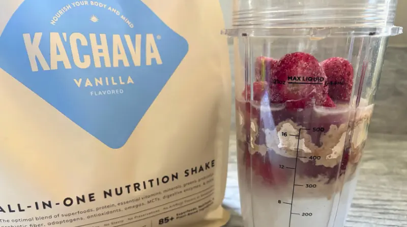 bag of kachava pictured next to a a blender bottle with strawberries water and kachava powder